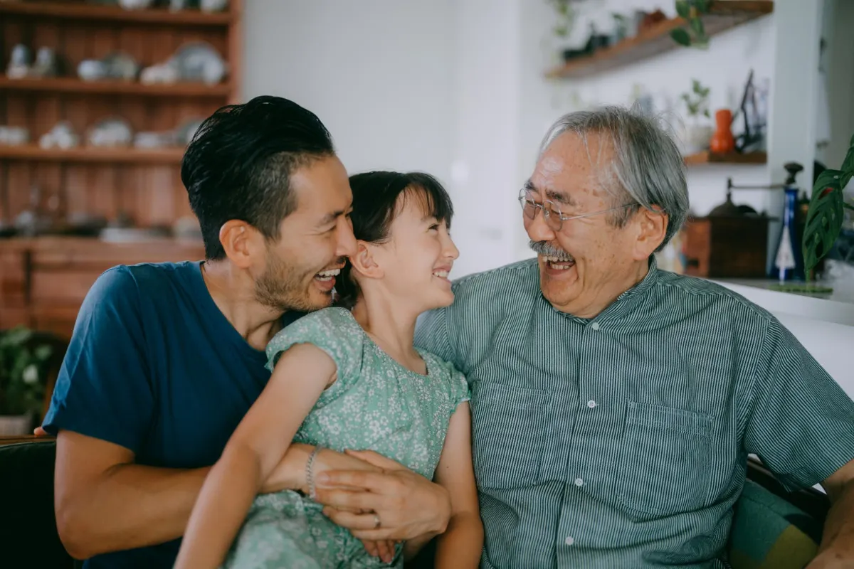Three generations of a family laughing together at home